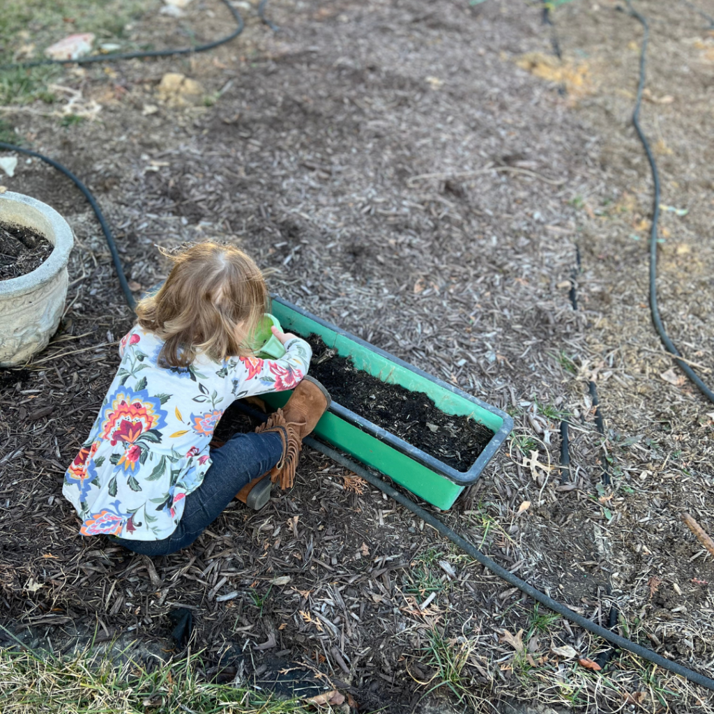 baby girl in fower shirt diggint in the garden